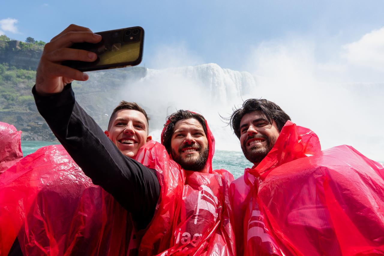 Three guests take a selfie in front of the American Falls on the Hornblower.